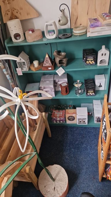 Display of various decorative items and gifts on a green shelf in a shop setting.